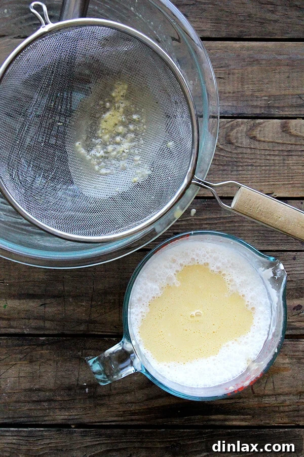 The egg mixture being strained through a fine-mesh sieve into the crème fraîche and milk for a silky custard.