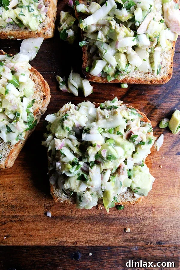 Creamy Avocado Smoked Trout Toasts 12 A close-up view of a smoked trout and avocado toast, highlighting the texture of the salad and the golden-brown bread underneath.