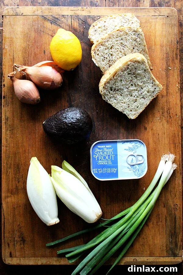 Creamy Avocado Smoked Trout Toasts 4 Fresh ingredients laid out, ready for preparing the smoked trout and avocado salad: shallots, lemon, endive, scallions, parsley, avocado, and tins of smoked trout.