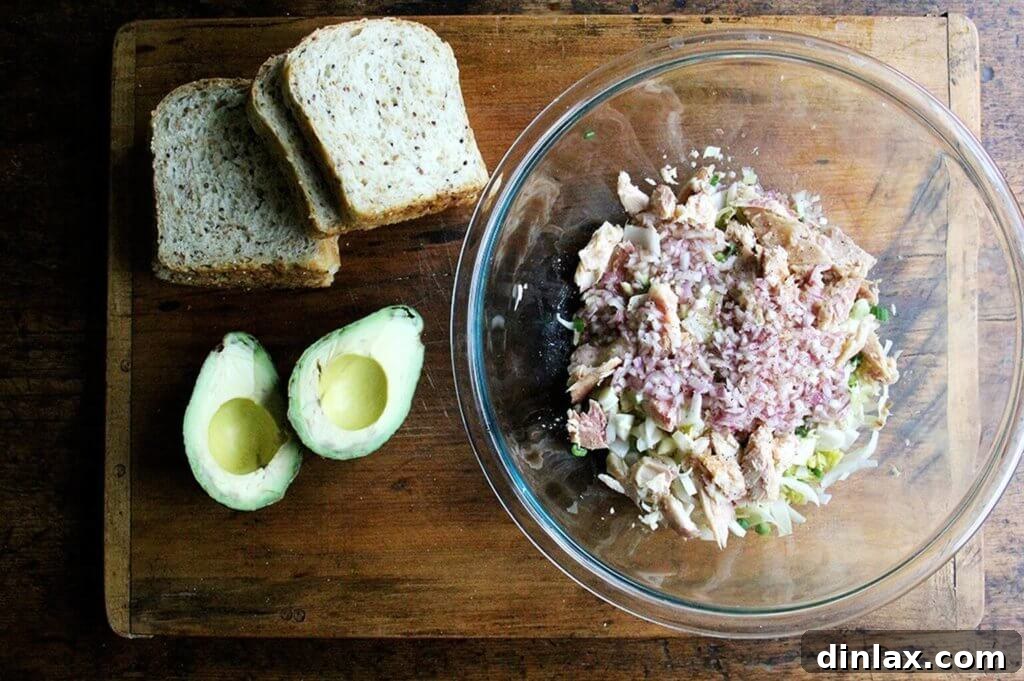 Creamy Avocado Smoked Trout Toasts 6 Flaked smoked trout being added to the bowl with endive and scallions, ensuring generous pieces for texture.