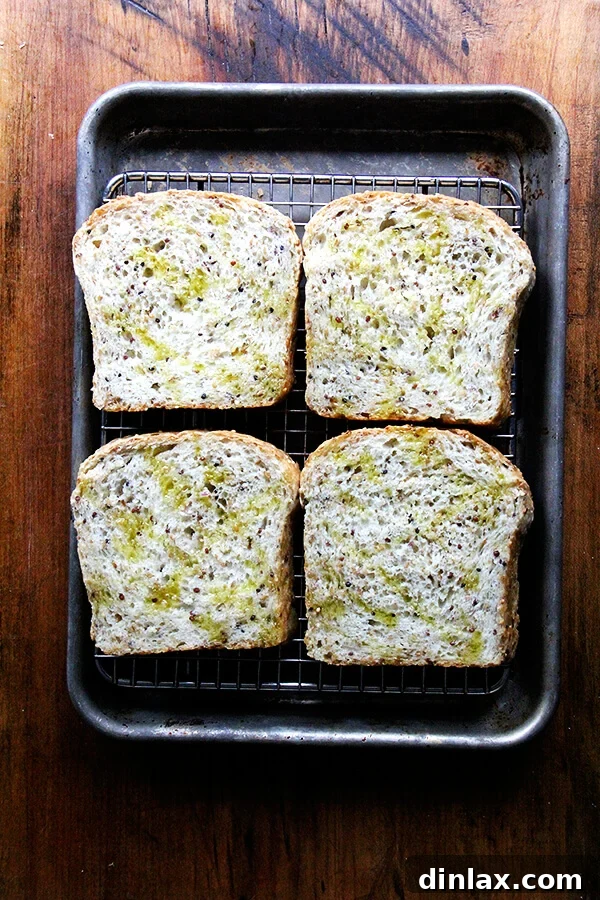 Creamy Avocado Smoked Trout Toasts 9 Slices of quinoa-flax bread arranged on a cooling rack set on a sheet pan, ready for broiling to achieve golden perfection.