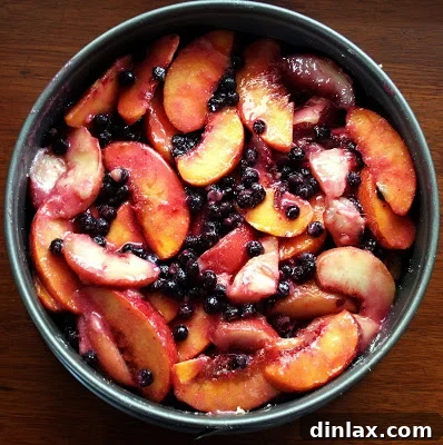The unbaked peach blueberry cake, beautifully arranged with fruit on its pastry base, poised for the oven.