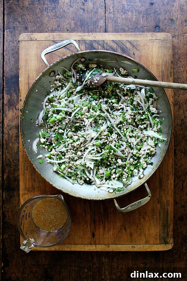 Close-up of freshly made Larb Gai, the Thai chicken salad, served in a bowl with lettuce leaves on the side, ready for wrapping. Vibrant colors of herbs, chilies, and chicken.