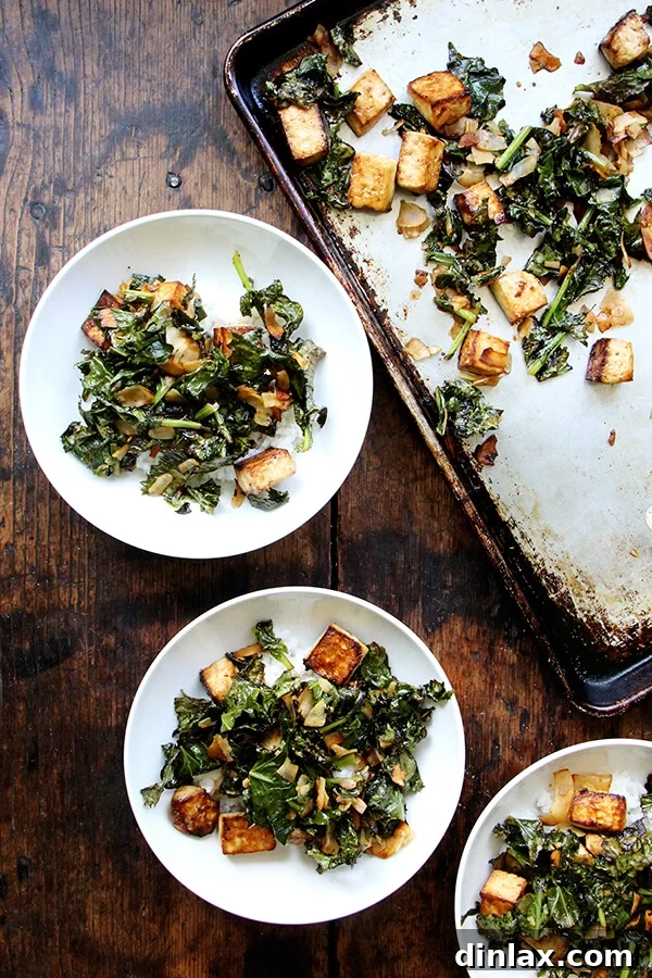 Close-up of crispy baked tofu, vibrant roasted Tuscan kale, and golden toasted coconut on a sheet pan, freshly removed from the oven and ready to be served. A perfect sheet pan dinner.