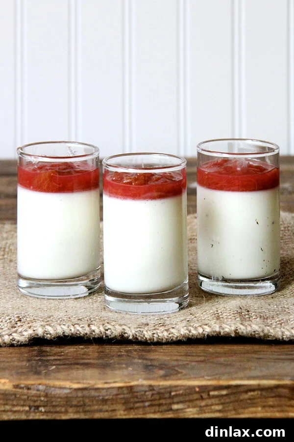 Three individual glasses of buttermilk panna cotta, each beautifully topped with rhubarb compote and ready for serving.