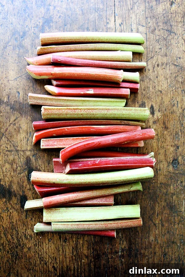 Freshly picked rhubarb stalks laid out on a wooden cutting board, ready for preparation.