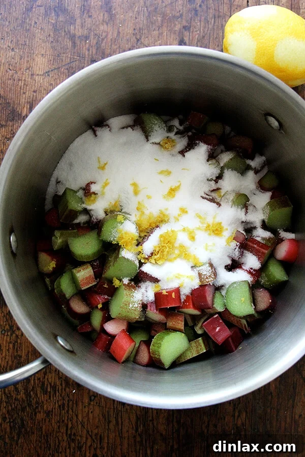 Chopped rhubarb, granulated sugar, and lemon zest simmering in a saucepan.