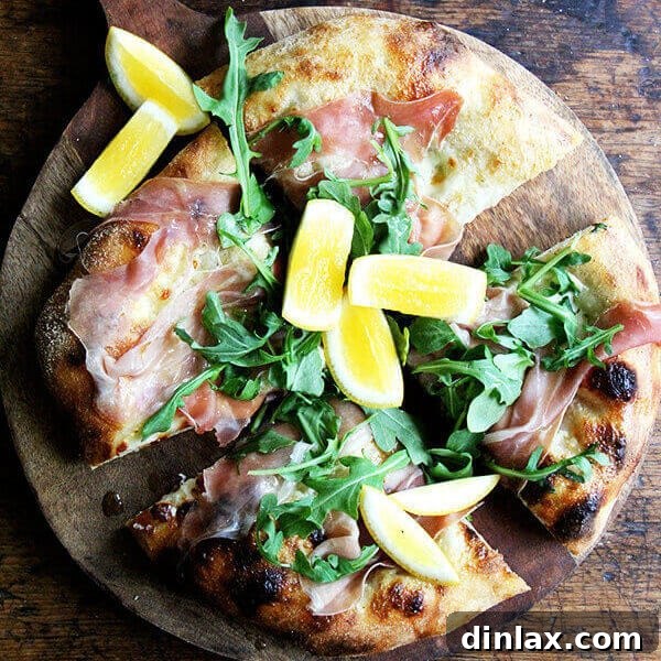 A beautifully baked pizza with a golden crust, melted mozzarella, topped with fresh green arugula and delicate slices of prosciutto.