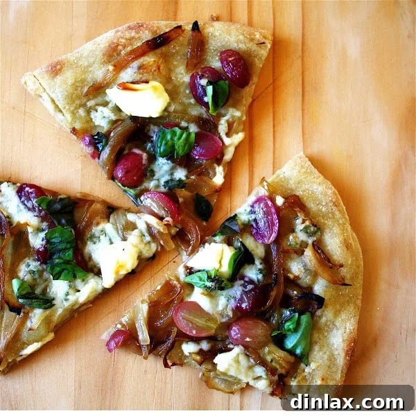 Crispy thin-crust pizza topped with caramelized onions, grapes, gorgonzola, and mascarpone cheese, fresh out of a high-temperature oven.