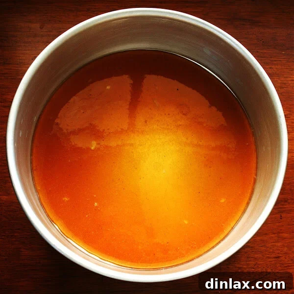 Thinly sliced ripe pears, meticulously arranged in concentric circles, ready to be layered over the caramel base for the Gateau Tiede Aux Poires.