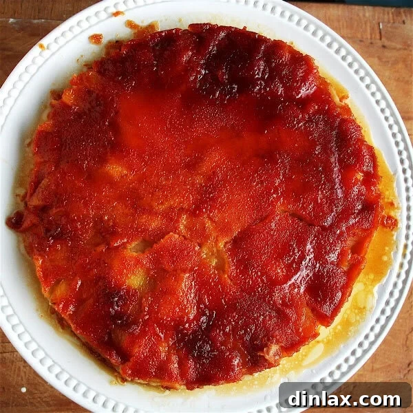 A slice of Gateau Tiede Aux Poires Mas De Cure Bourse on a plate, showing the layers of caramelized pears and golden custardy cake, ready to be served.