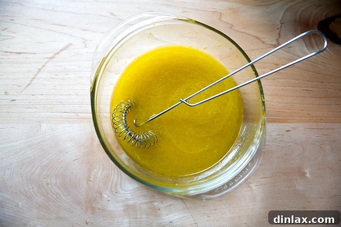 Wet ingredients for orange and olive oil cake whisked together in a bowl, showing a smooth emulsion.