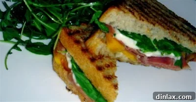 Close-up of the assembled persimmon panini before grilling, showing clear layers of mascarpone, persimmon, prosciutto, mozzarella, and arugula.