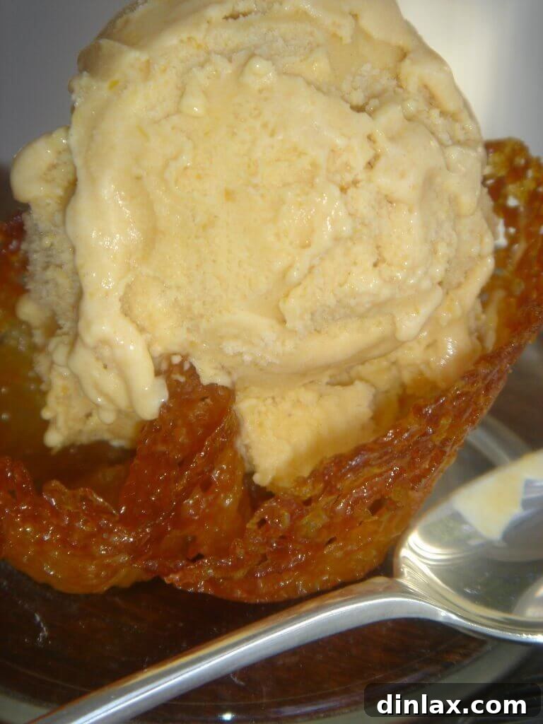 Spiced Pumpkin Delight 2 A scoop of rich, creamy homemade pumpkin ice cream, nestled perfectly in a delicate almond cookie cup, garnished with a hint of cinnamon.