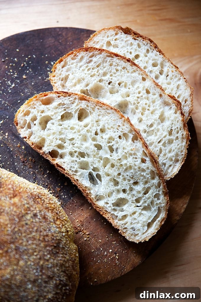 A sliced loaf of Jim Lahey's No-Knead Bread on a cutting board, revealing its signature airy crumb and open texture.