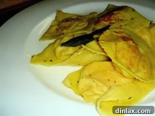Delicious homemade butternut squash ravioli with sage brown butter sauce, garnished with crispy sage leaves.