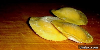 Freshly made pasta dough being kneaded on a wooden board, ready for shaping into ravioli.