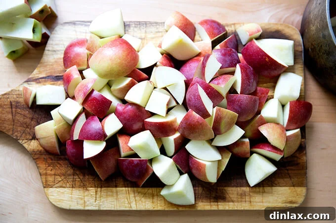 Warm Spiced Applesauce 4 Freshly cut apple chunks, with skins intact, neatly arranged on a wooden board.