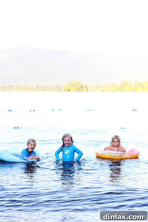 The Queen of American Lakes 3 A group of happy children playing and splashing joyfully in the refreshing, crystal-clear waters of Lake George, perfectly capturing a summer vacation moment.