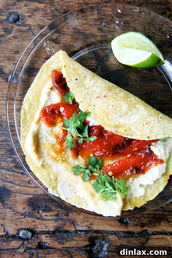 A vibrant roasted red pepper and white bean hummus wrap, freshly prepared and bursting with flavor.