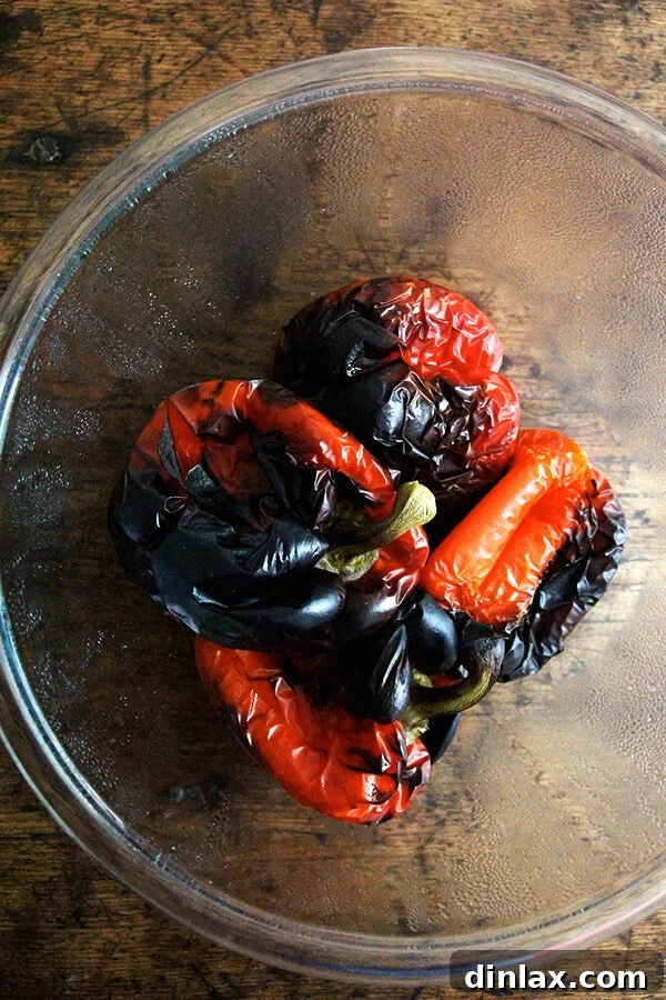 Perfectly charred red bell peppers fresh from the oven, ready for the steaming process.
