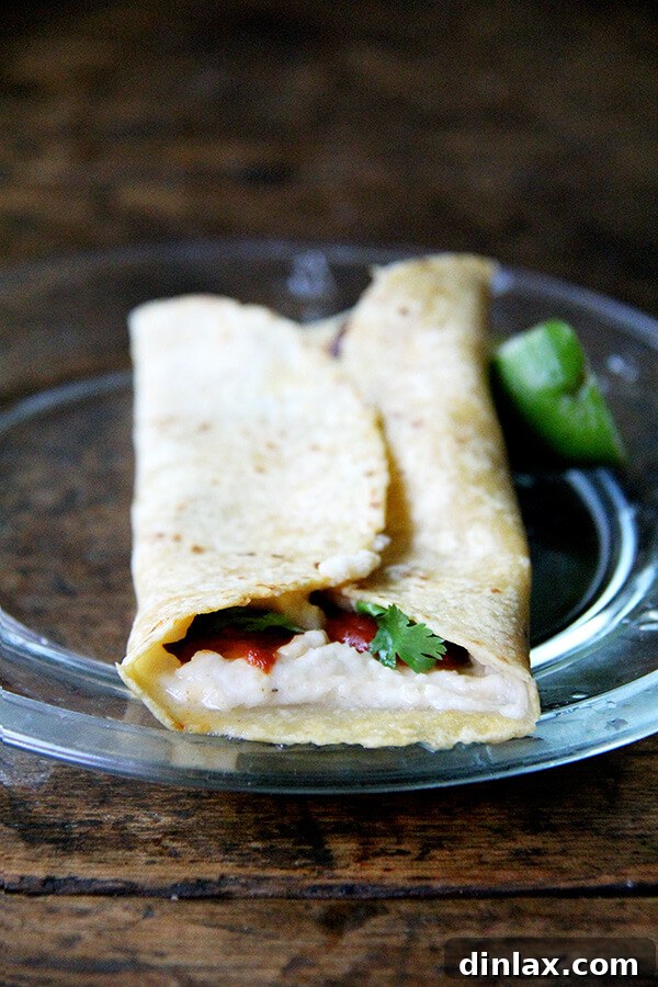 Close-up of a roasted red pepper and white bean hummus wrap, showing the colorful filling and soft tortilla.