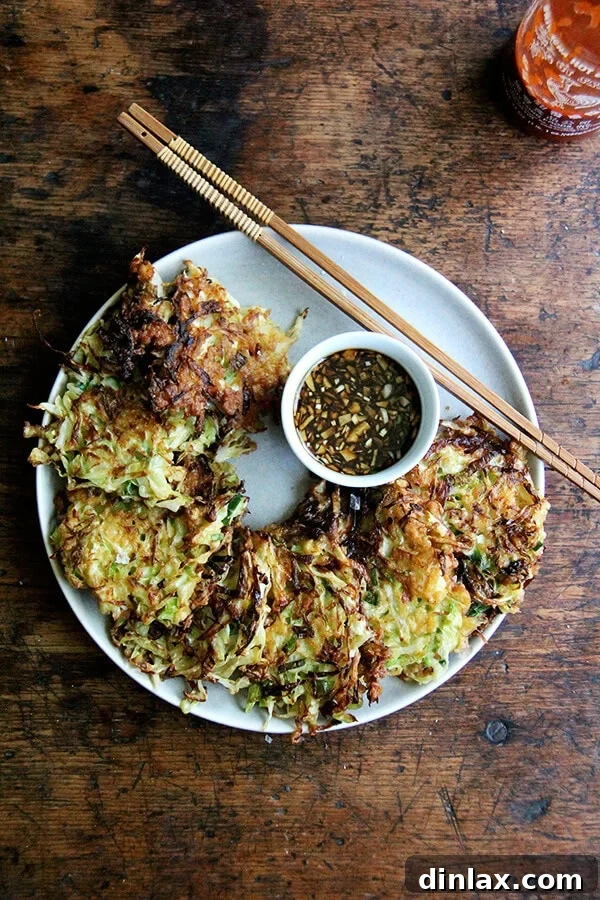 A plate of freshly prepared Okonomiyaki, Japanese cabbage pancakes, with a side of savory soy dipping sauce.