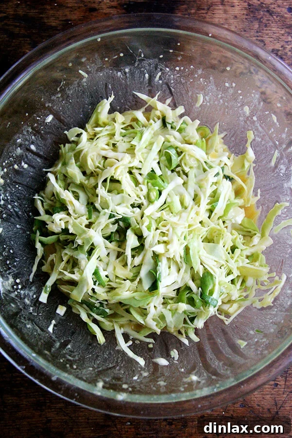 Okonomiyaki batter, a mixture of eggs, flour, cabbage, and scallions, in a large bowl.