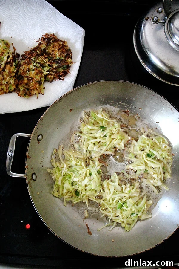Several cabbage pancakes frying in a large skillet, golden brown and sizzling.