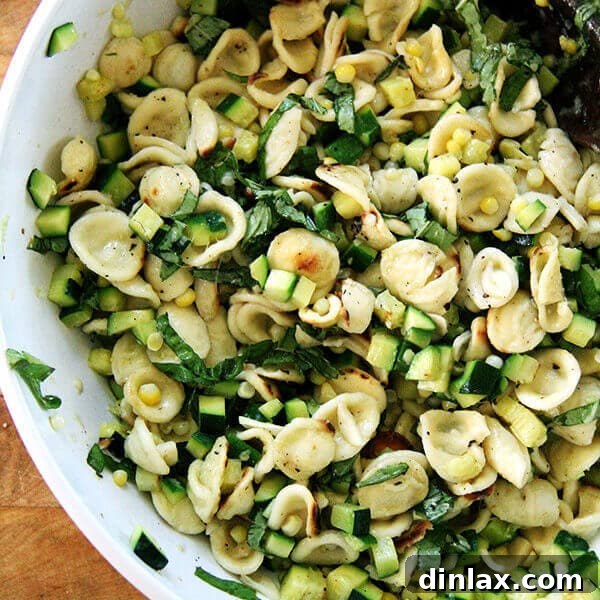 Close-up of vibrant Toasted Orecchiette with Zucchini and Corn, generously garnished with fresh basil leaves.