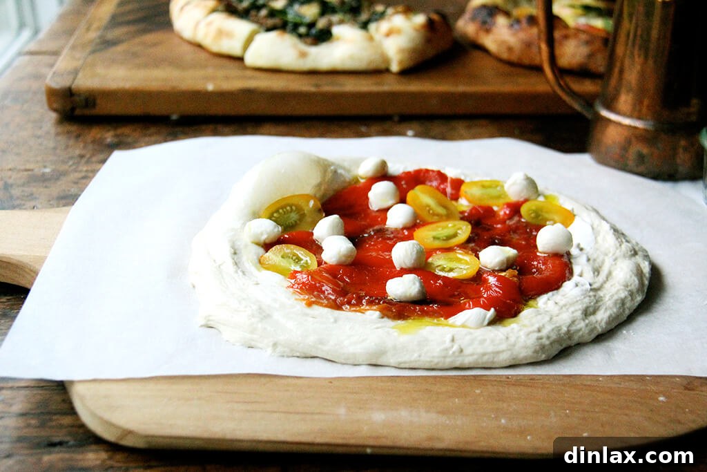 Gourmet roasted red pepper and tomato pizza, generously topped with colorful vegetables and cheese, exhibiting a golden, crispy crust.