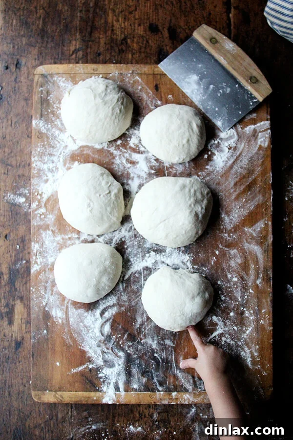Hands meticulously dividing fresh Lahey no-knead pizza dough into perfectly sized individual portions, preparing for optimal storage and future use.