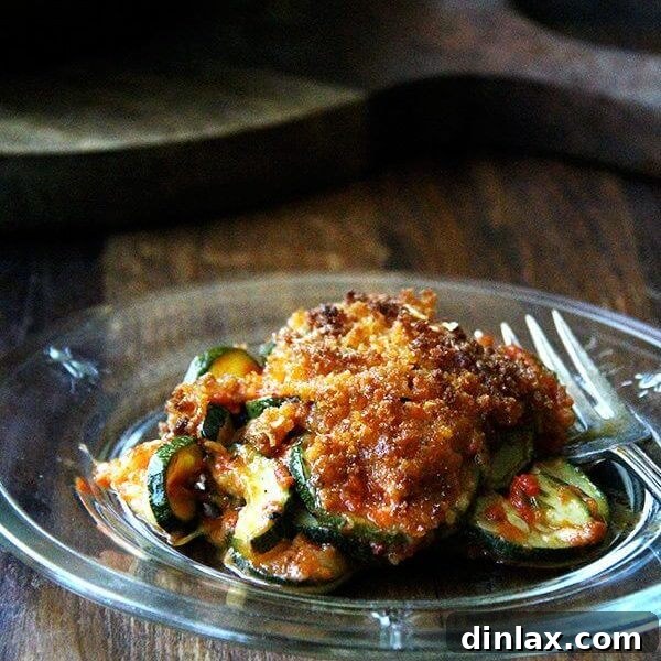A slice of golden Zucchini Parmesan gratin with layers of roasted zucchini and rich sauce.