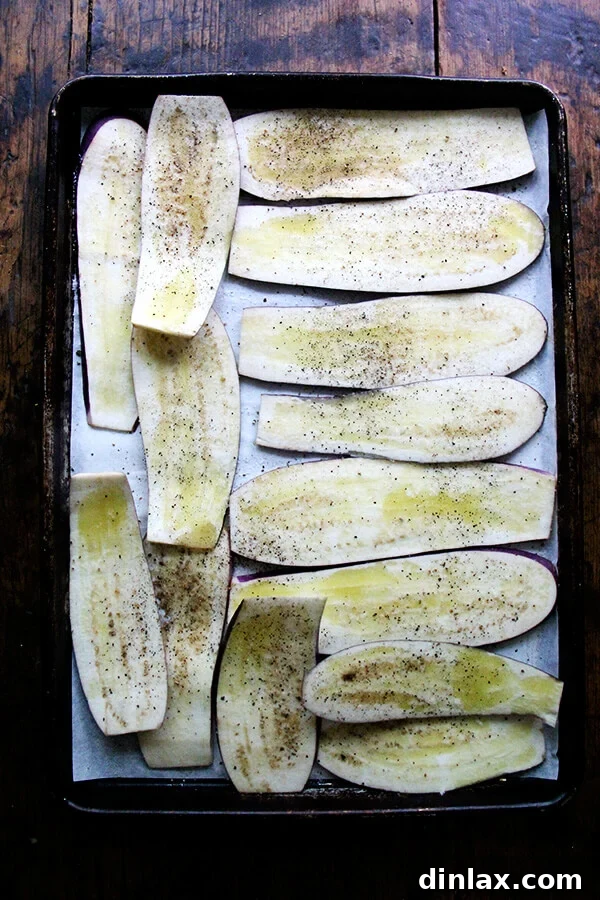 Sliced eggplant arranged neatly on a sheet pan, ready for roasting.