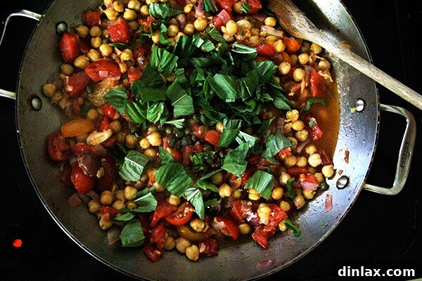 Mediterranean Chickpea and Tomato Stew with Feta 3 Fresh tomatoes, vibrant basil leaves, and briny capers join the chickpeas and aromatics in the sauté pan, ready to create a flavorful stew base.