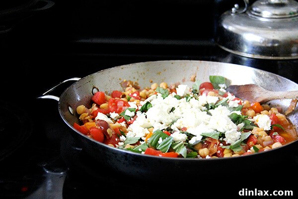 Mediterranean Chickpea and Tomato Stew with Feta 4 Crumbled feta cheese generously tops the simmering chickpea and tomato stew, preparing to melt into creamy pockets of flavor.