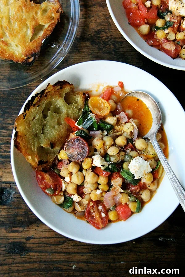 Mediterranean Chickpea and Tomato Stew with Feta 6 A beautifully presented bowl of stewy chickpeas with tomatoes, basil, and feta, served alongside olive oil-toasted crusty bread, ready to be enjoyed.