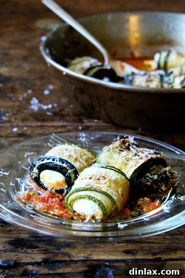 A close-up of a plate of zucchini involtini, garnished with fresh herbs and cheese.