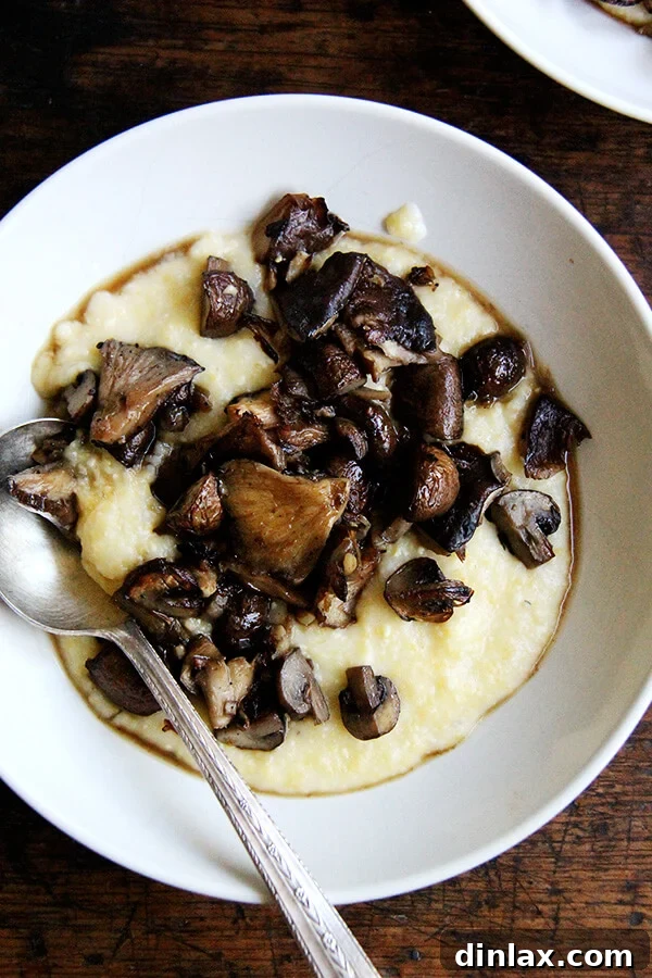 A heartwarming bowl of roasted mushrooms served over a bed of creamy, golden polenta, garnished with fresh herbs.
