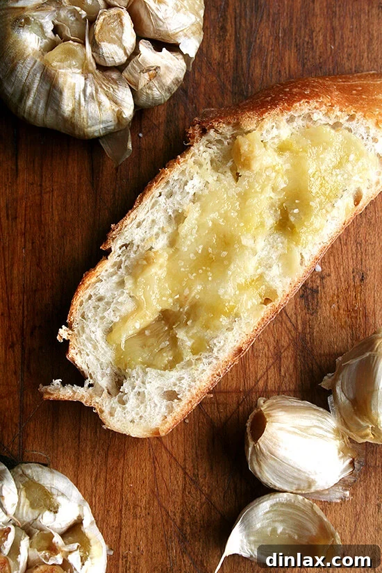 Warm, golden-brown bread generously spread with tender, mashed whole roasted garlic cloves, ready to be savored.