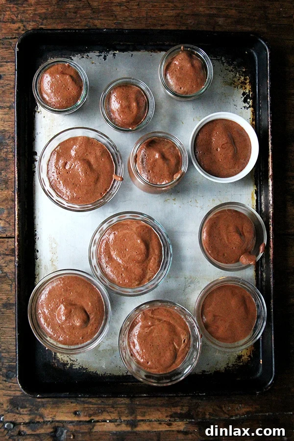 A tray of individual servings of creamy vegan chocolate mousse, garnished lightly. The mousse appears light and airy, hinting at its delightful texture.