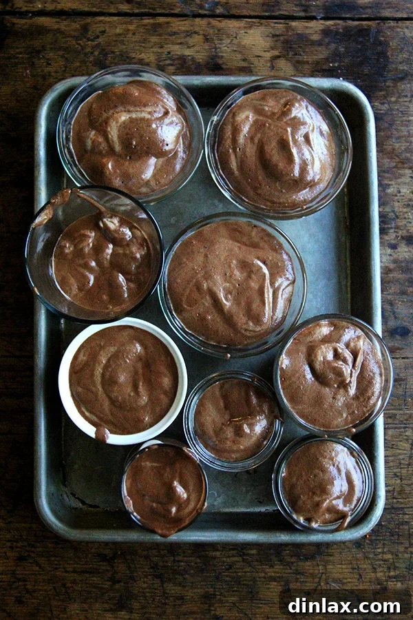 A sheet pan arrayed with multiple small bowls filled with homemade vegan chocolate mousse, crafted using homemade aquafaba.