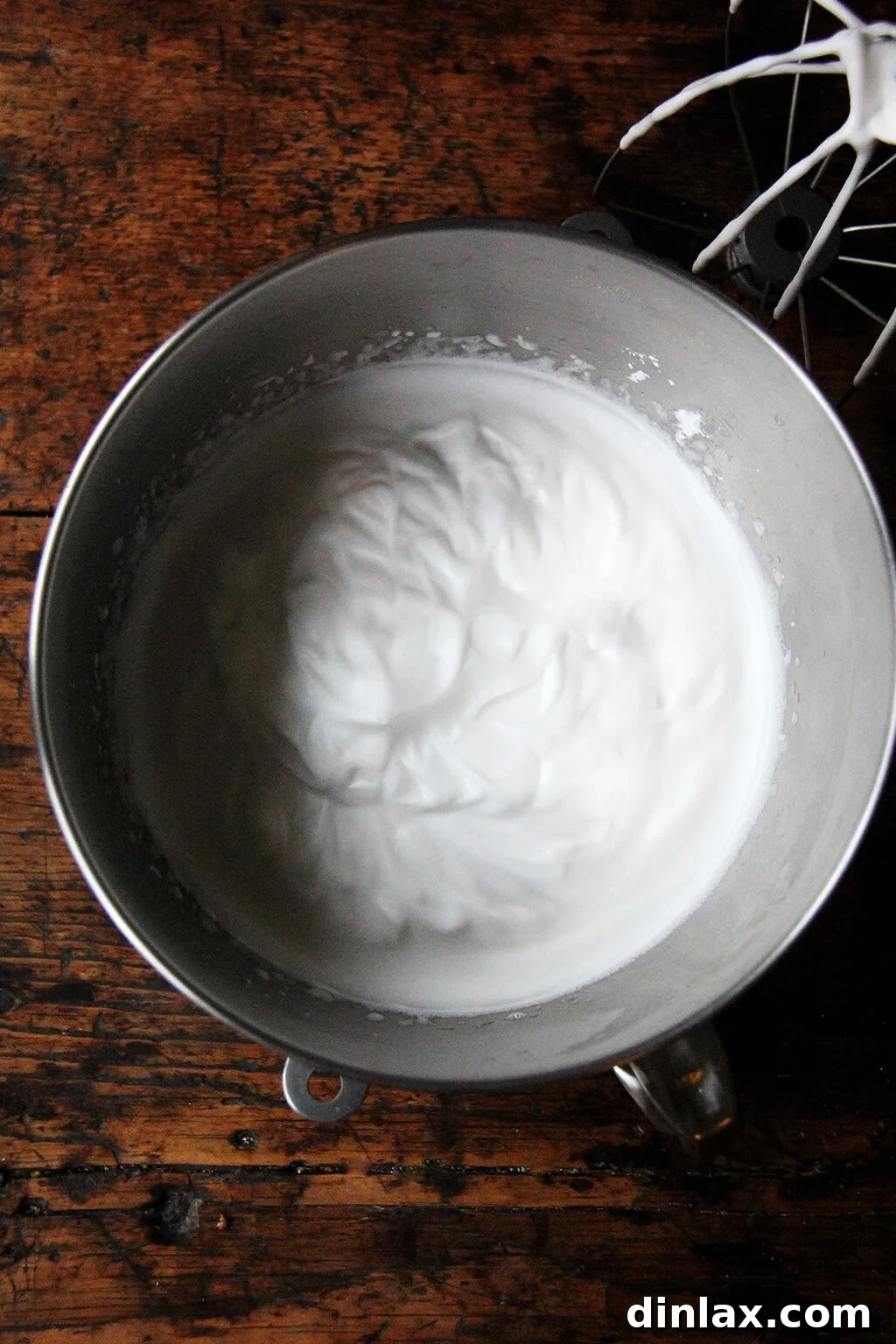 A gleaming stand mixer bowl overflowing with perfectly whipped aquafaba, showcasing its pristine white, stiff peaks.
