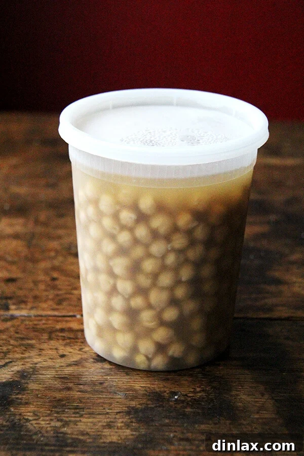 A container of chickpeas that have been cooked from scratch, still in their liquid, ready for separation.
