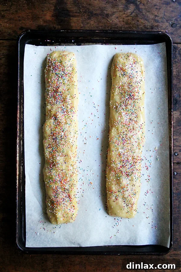 Sweet and Salty Marzipan Mandel Bread 5 Mandel bread dough logs, sprinkled with decorative toppings, ready for the first bake.