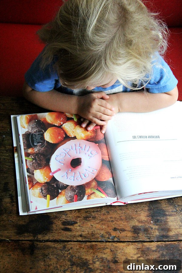 A child, Wren, looking intently at the book 'How to Celebrate Everything', perhaps pointing at a page.