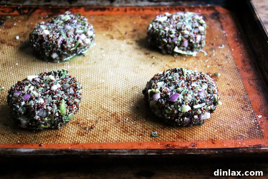 Shaped crispy quinoa cakes, ready for cooking, neatly arranged on a parchment-lined baking sheet.