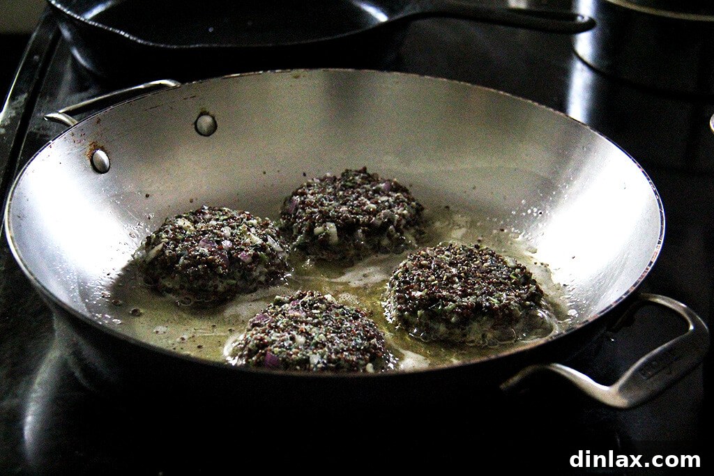 Crispy quinoa cakes frying in a hot skillet, golden brown and sizzling.