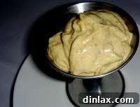 Close-up shot of a small bowl of homemade spicy aioli, showcasing its creamy texture and flecks of herbs or spices, ready to accompany fries or steak.
