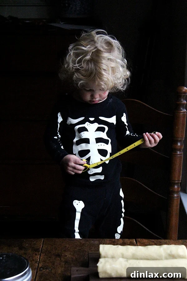 Dorie Greenspan's Classic Vanilla Bean Sablés 9 A child dressed in playful skeleton pajamas, holding a tape measure, possibly helping with cookie dough measurements.